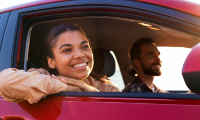 a person driving and a person looking out of the window of a red car