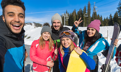 young men and women friends with skiing equipment take selfie