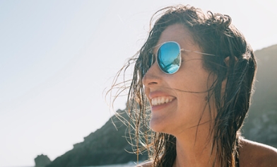 Woman wearing sunglasses and smiling with mountains in distance