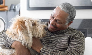 A man cuddles his pet dog on a sofa