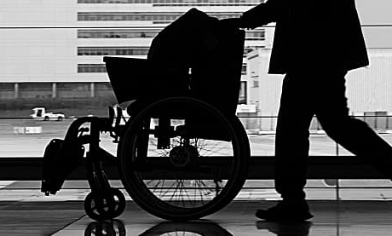 Person pushing wheelchair along passage in airport