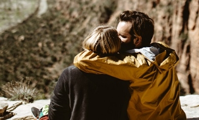 Couple sitting on rock hill, embracing