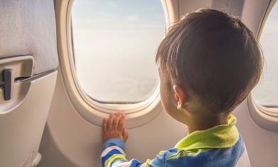 Young boy sitting in airplane looking out of airplane window