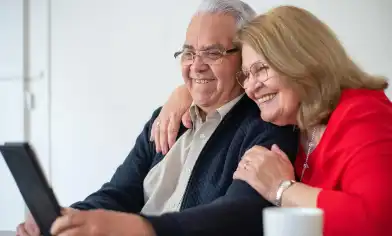 Elderly couple smiling while looking at an electronic tablet
