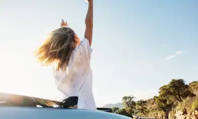 lady waving her arms in an open top car