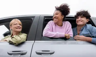 a driver and two passengers all leaning out of windows and smiling