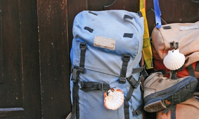 Two backpacks, one with boots attached, sat against a dark wooden door
