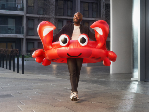 A person walking with a very large red inflatable crab