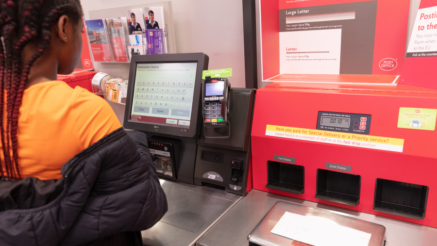 Female customer using a self service kiosk in a Post Office branch