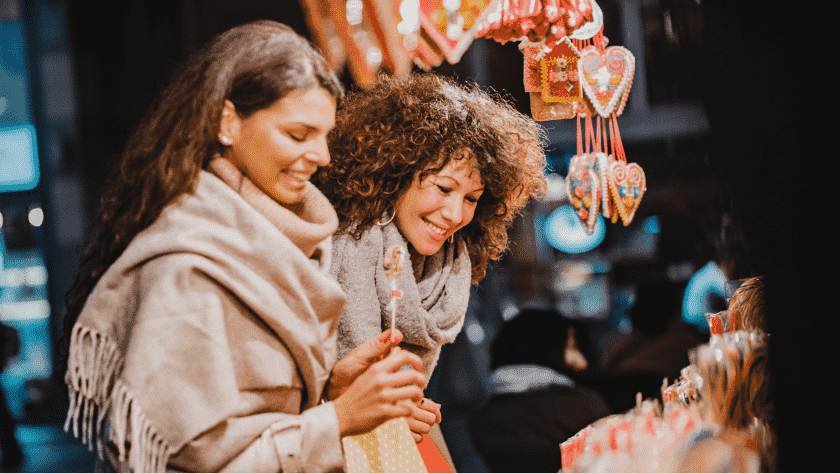 Two young smiling women in a Polish market looking a goods on sale