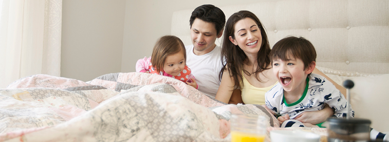 Young family laughing in bed together