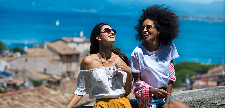 Two women laughing, enjoying each other's company, behind them, the sea view from above