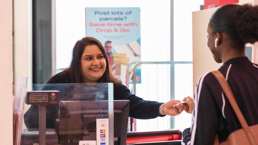 Female Post Office worker at a counter serving a young female customer