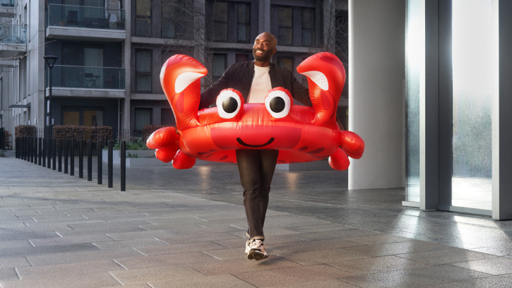 A person walking with a huge red inflatable crab