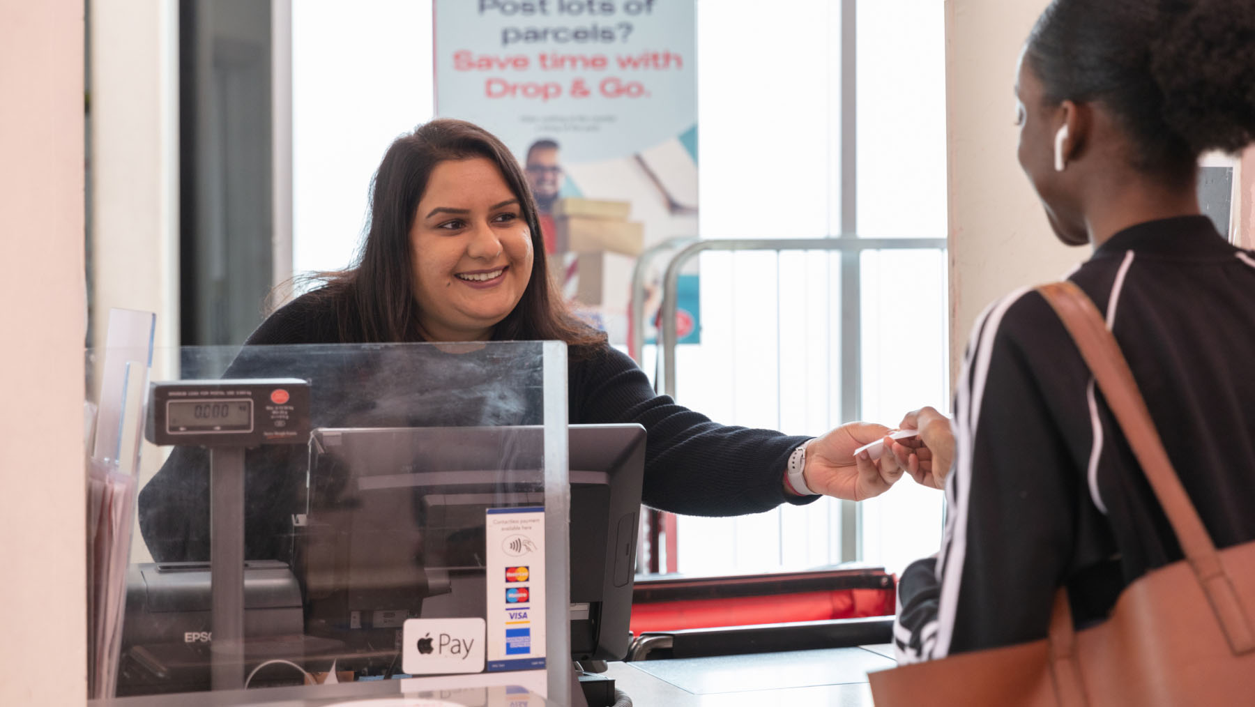 Post office staff serving a customer in branch