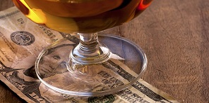 Glass full of drink sat on top of a United States five-dollar bill, left as a tip, on a table