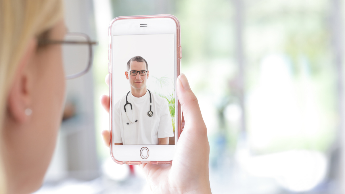 Female wearing glasses looking at her phone on a video call with a doctor