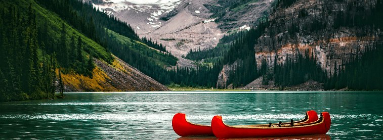 Canadian kayaks in water surrounded by Canadian mountains and trees