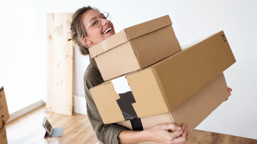 Smiling woman wearing glasses holding a stack of parcels