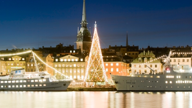 Christmas tree on harbour, flanked by two large boats at night