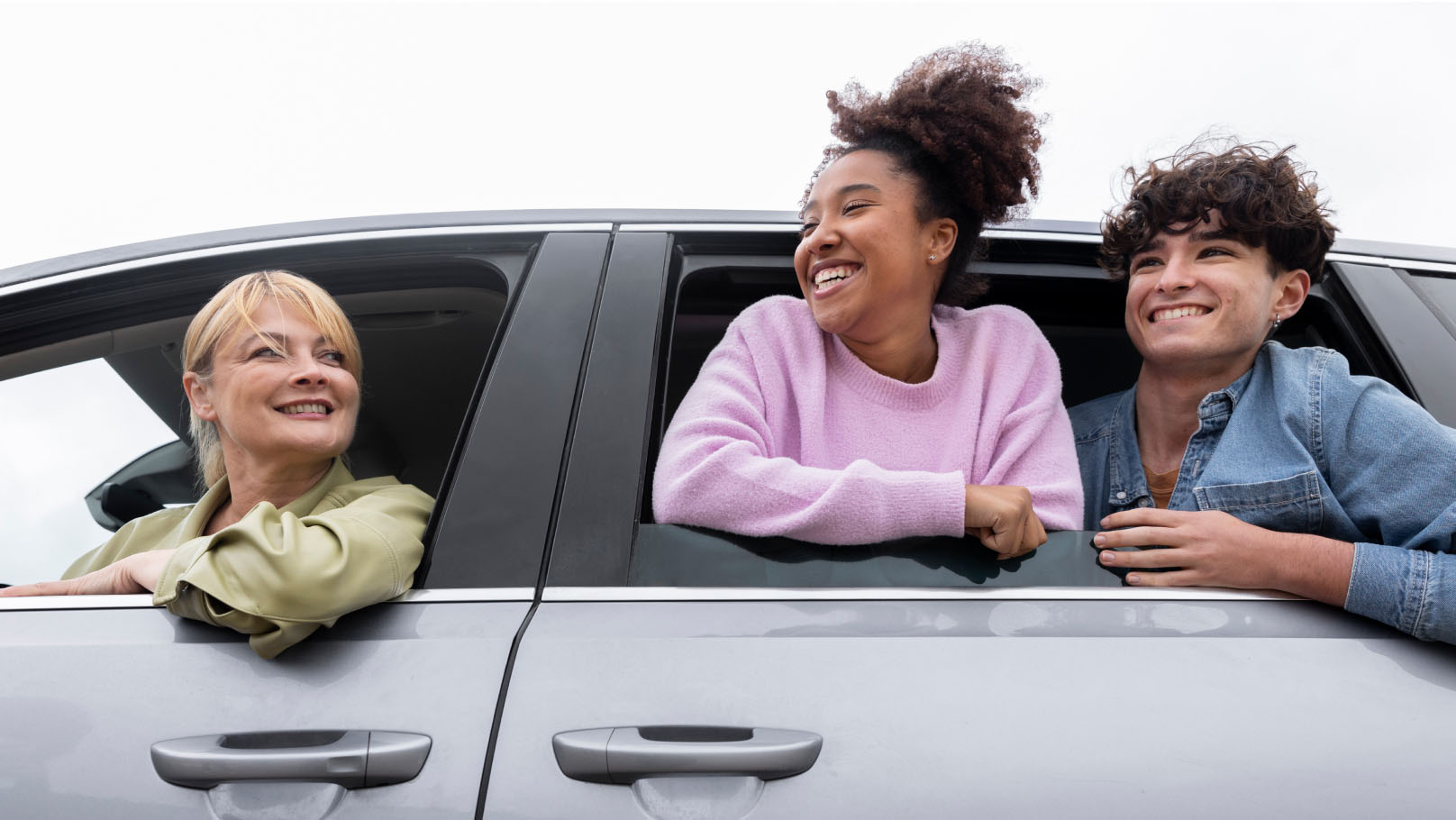 a driver and two passengers all leaning out of windows and smiling