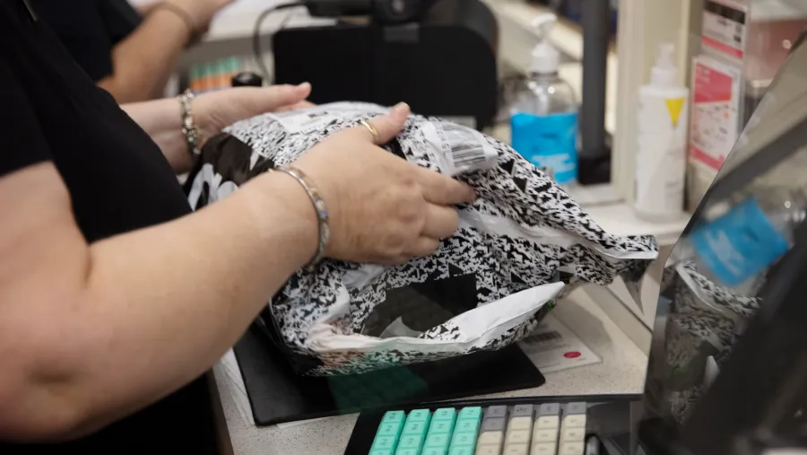 Member of Post Office staff handling a pre-paid labelled ASOS package