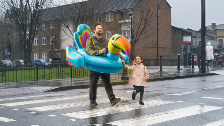 a person wearing a large blue tucan pool float walking with a child