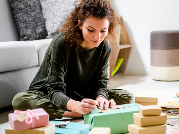 Woman sat on a lounge floor wrapping parcels of varying sizes