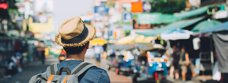 Male wearing hat and backpack looking in to distance ahead of him