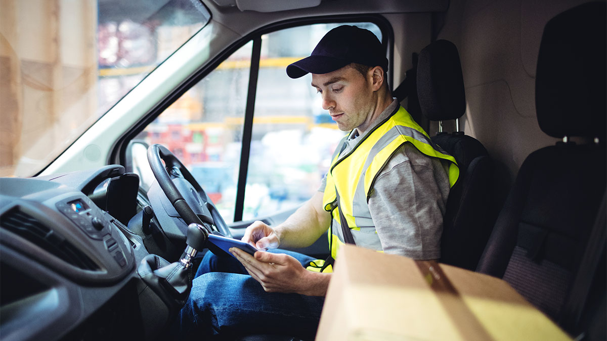 Man in vehicle sitting in the driver seat, looking at his tablet