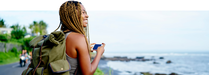 Woman enjoying the view whilst preparing to take a camera phone image of the coastline