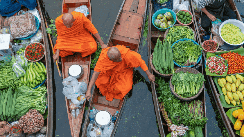 Overhead view of Thailand boat market focused on two Thai vendors selling various product