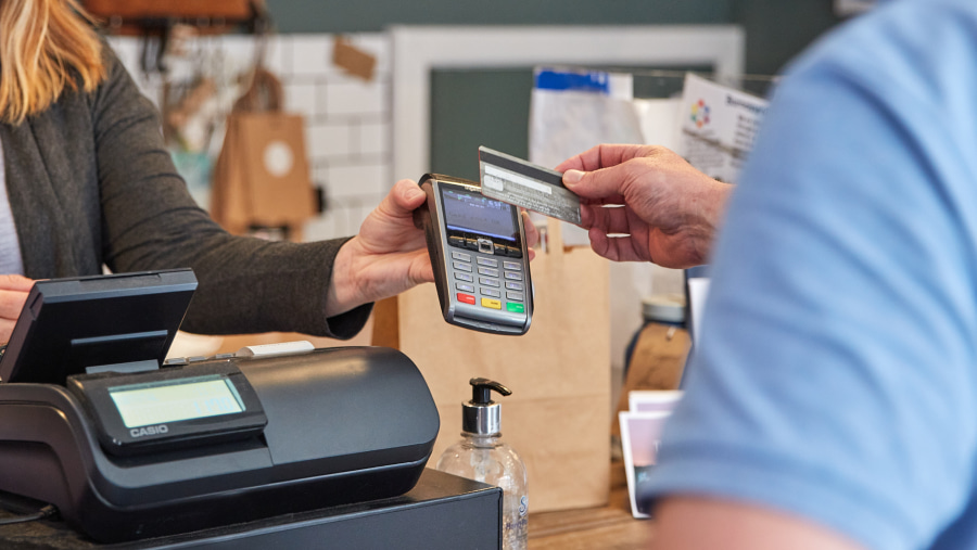 A member of Post Office staff holding a card terminal up for the customer to make payment