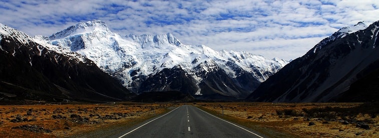 New Zealand road with snow-capped mountains either side and ahead