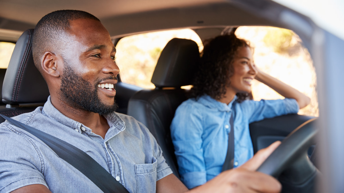 Man driving car, woman sitting in the front passenger seat, both smiling