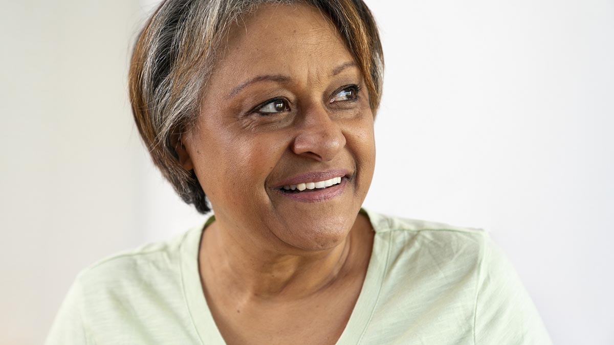 A person wearing a light-colored shirt, standing against a plain, light-colored background