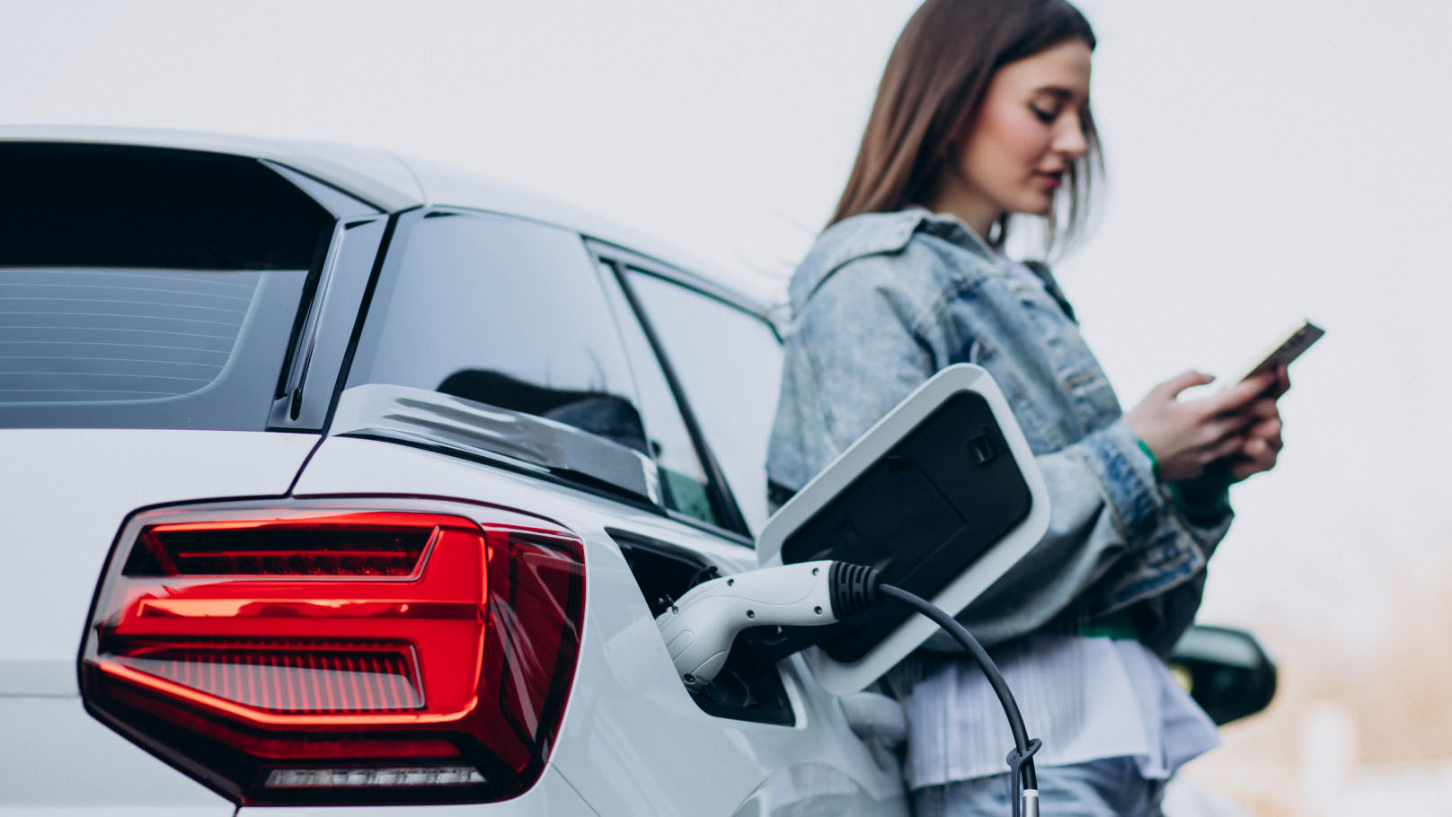 Woman charging her electric car with charging pistol