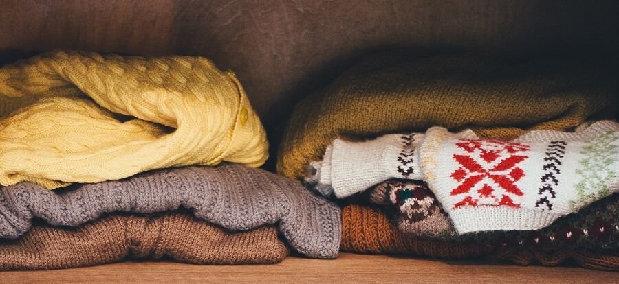 Various jumpers piled up on a clothes shelf