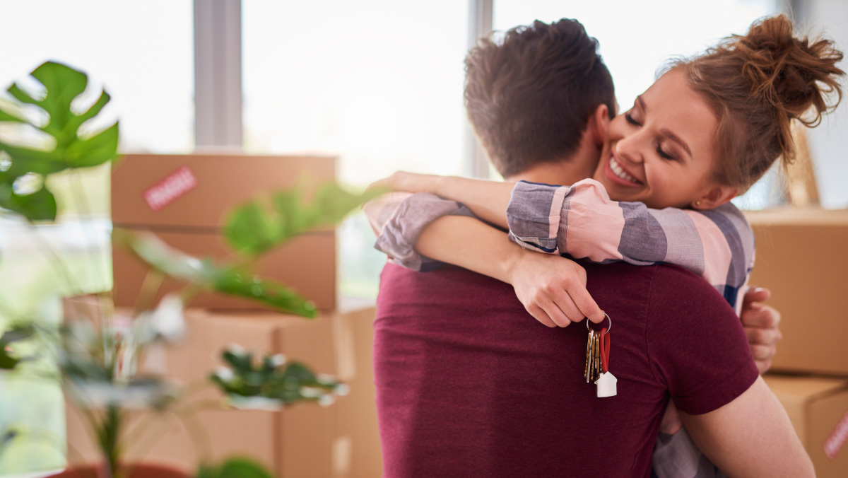 couple hugging with boxes and a plant nearby