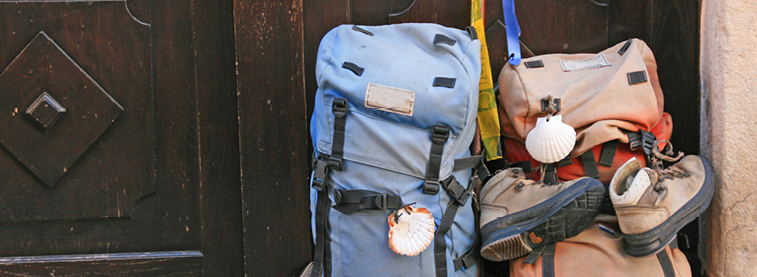 Two backpacks, one with boots attached, sat against a dark wooden door