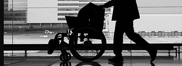 Person pushing wheelchair along passage in airport