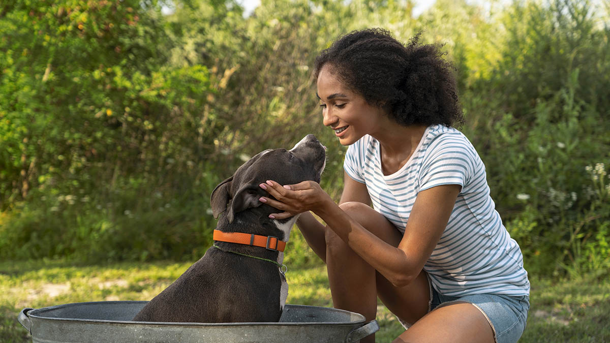 a pet owner cradling the head of her dog while in a bathtub outdoors