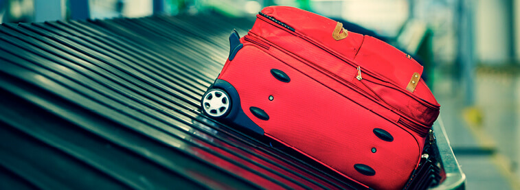 Red suitcase on airport conveyor belt at luggage reclaim