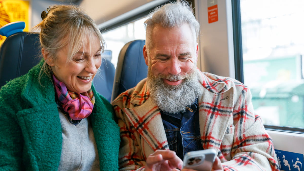 Man and woman laughing looking at phone, held by the man in his hand