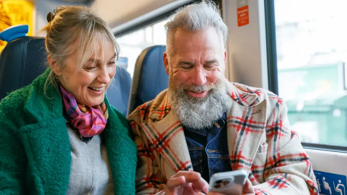 Man and woman laughing looking at phone, held by the man in his hand
