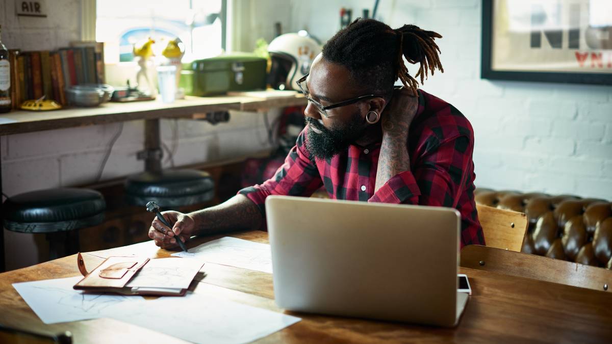 A man sat at a desk with laptop and papers