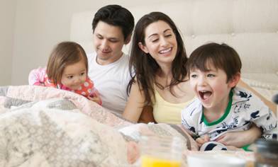 Young family laughing in bed together