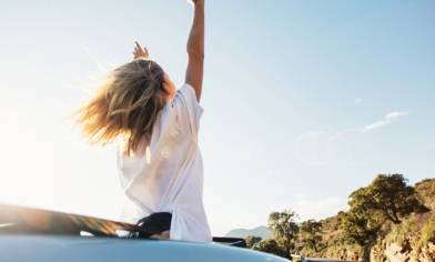 lady waving her arms in an open top car