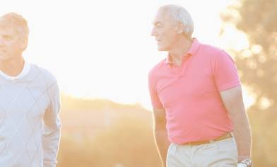 Two mature men standing outside, on a bright morning