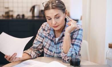 A person sitting at a table reading a document, pen in hand